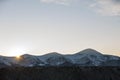 Winter mountains landscape panorama at sunrise. Clear blue sky over dark spruce pine trees forest, covered with snow mountain Royalty Free Stock Photo