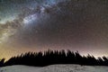 Winter mountains night landscape panorama. Milky Way bright constellation in dark blue starry sky over dark spruce pine trees Royalty Free Stock Photo