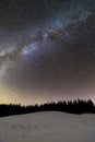 Winter mountains night landscape panorama. Milky Way bright constellation in dark blue starry sky over dark spruce pine trees Royalty Free Stock Photo