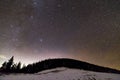 Winter mountains night landscape panorama. Milky Way bright constellation in dark blue starry sky over dark spruce pine trees Royalty Free Stock Photo