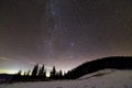 Winter mountains night landscape panorama. Milky Way bright constellation in dark blue starry sky over dark spruce pine trees Royalty Free Stock Photo