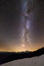 Winter mountains night landscape panorama. Milky Way bright constellation in dark starry sky, soft glow on horizon after sunset, Royalty Free Stock Photo