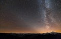 Winter mountains night landscape panorama. Milky Way bright constellation in dark starry sky, soft glow on horizon after sunset, Royalty Free Stock Photo