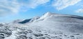 Winter mountains ridge with overhang snow caps and snowboard tracks on blue sky background. Ukraine, Carpathians, Svydovets Range