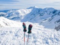 Winter mountains and ski gloves on ski poles on foreground