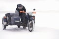 A winter nature trip on a motorcycle with a side trailer. A man pushes a bogged motorcycle out of a snowdrift. Blizzard. Royalty Free Stock Photo