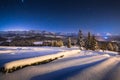 Winter night landscape. Starry blue night sky over winter mountains. Christmas night scenery in mountains