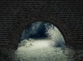 Winter night snowy rural road through a stone arch in the wall