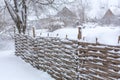 Winter old shabby wobbly wicker fence made of wooden boards. Snow blizzard Royalty Free Stock Photo