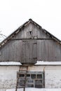 Winter. Old village house, view from the outside of an attic from wooden planks. The roof is covered with snow Royalty Free Stock Photo