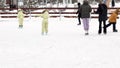 Winter open, skating rink a lot of people skate, twin children learn to skate, stumble, fall.