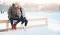 Winter outdoor activities. Loving couple girl and young man ice skating rink, in background sunlight Royalty Free Stock Photo