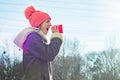 Winter outdoor portrait of young girl screaming in a megaphone paper cup, copy space Royalty Free Stock Photo