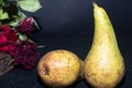 Winter pears brutally brown. Near dried maroon roses. On a dark background