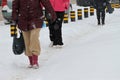 Winter. People walk on a very snowy sidewalk and road. People step on an icy pathway, icy sidewalk. Uncleaned streets and roads