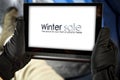 Winter photo of tablet held in hands in black gloves and spce for products, text and decorations.