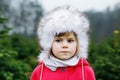 Winter portrait of adorable cute toddler girl of three years. Beautiful baby with cute fur hat looking and smiling at Royalty Free Stock Photo