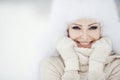 Winter portrait of beautiful smiling woman with snowflakes in white furs