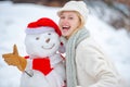 Winter portrait of beauty girl in snow Garden. Girl in snow. People in snow. Happy snowman standing in winter Christmas Royalty Free Stock Photo