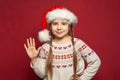 Winter portrait of cheerful happy child girl in Santa hat. Kid says hello Royalty Free Stock Photo