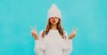 Winter portrait close up of cheerful woman pulling white hat over her eyes wearing a knitted sweater on blue Royalty Free Stock Photo