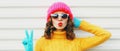 Winter portrait close up of young woman blowing red lips sending sweet air kiss wearing a pink hat, yellow sweater Royalty Free Stock Photo