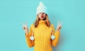 Winter portrait cool young woman having fun pulls a hat over her eyes wearing yellow knitted sweater and white hat with pom pom