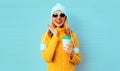 Winter portrait delighted smiling young woman with coffee cup wearing yellow knitted sweater, white hat with pom pom Royalty Free Stock Photo