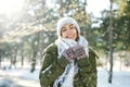 Winter portrait of funny smiling woman in woolen hat and long warm scarf in snowy winter park. Flying snowflakes. Royalty Free Stock Photo