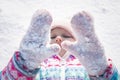 Little cheerful girl, 7-8 years old, in bright winter overalls, sits on the snow