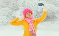 Winter portrait of happy cheerful smiling young woman 20s taking selfie with mobile phone wearing knitted sweater, hat and scarf Royalty Free Stock Photo