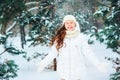 Winter portrait of happy child girl in white coat, hat and mittens playing outdoor in snowy winter forest Royalty Free Stock Photo