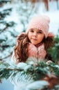 Winter portrait of happy kid girl in white coat and hat and pink mittens playing outdoor in snowy winter forest Royalty Free Stock Photo