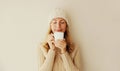 Winter portrait of happy satisfied young woman enjoying cup of hot tasty coffee or tea in warm knitted sweater and hat in early Royalty Free Stock Photo