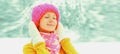 Winter portrait of happy smiling cute young woman wearing knitted hat, sweater and scarf enjoys outdoors on snowy park background Royalty Free Stock Photo