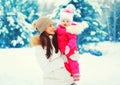 Winter portrait happy smiling mother with baby on her hands over snowy christmas tree Royalty Free Stock Photo