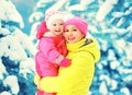 Winter portrait happy smiling mother holds baby on hands over snowy christmas tree