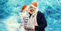 Winter portrait of happy smiling young couple hugging in red santa hats outdoors on christmas tree background with snowflakes Royalty Free Stock Photo