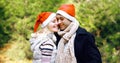 Winter portrait happy smiling young couple hugging in red santa hats outdoors on christmas tree background Royalty Free Stock Photo