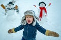 Winter portrait of little boy child in snow Garden make snowman. Child playing with Snowman on snow background. Winter Royalty Free Stock Photo