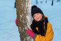 Winter portrait of a nice little girl near a tree. the child is wearing a winter hat Royalty Free Stock Photo