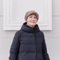 Winter portrait of smiling senior woman looking at camera, wearing faux pink fur cap. Royalty Free Stock Photo