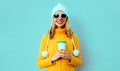 Winter portrait smiling young woman with coffee cup wearing yellow knitted sweater, white hat with pom pom Royalty Free Stock Photo