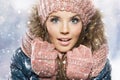 Winter portrait of young beautiful brunette woman wearing knitted snood covered in snow.