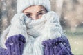 Winter portrait of young beautiful woman freezing and covering her face with woolen scarf on snowing winter day outdoors. Close-up Royalty Free Stock Photo
