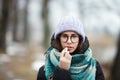 Winter portrait young cute brunette girl strolling winter forest park. Applying hygienic lipstick. Royalty Free Stock Photo