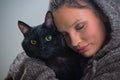 Winter portrait of young kind woman holding big black cat