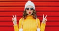 Winter portrait young woman blowing red lips sending sweet air kiss wearing yellow knitted sweater and white hat with pom pom Royalty Free Stock Photo