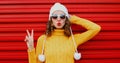 Winter portrait young woman blowing red lips sending sweet air kiss wearing yellow knitted sweater and white hat with pom pom Royalty Free Stock Photo