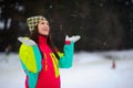 Winter portrait of the young woman in bright ski suit and a knitted cap.